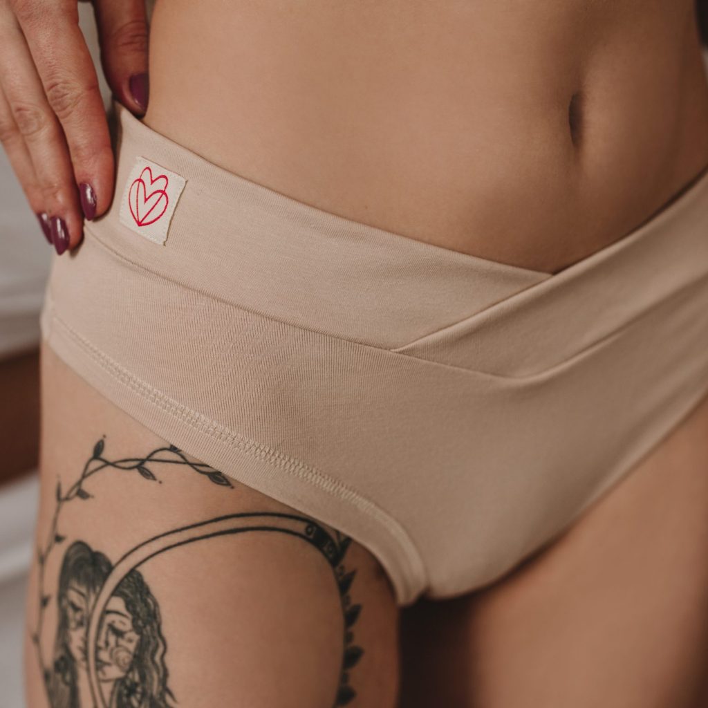 Detail telových nohavičiek Jane so širokým prekríženým pásom v tvare V na modelke.