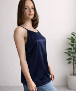 Tmavomodrá hodvábna košieľka s čipkovým lemom na modelke v džínsoch, pohľad v miernom natočení.